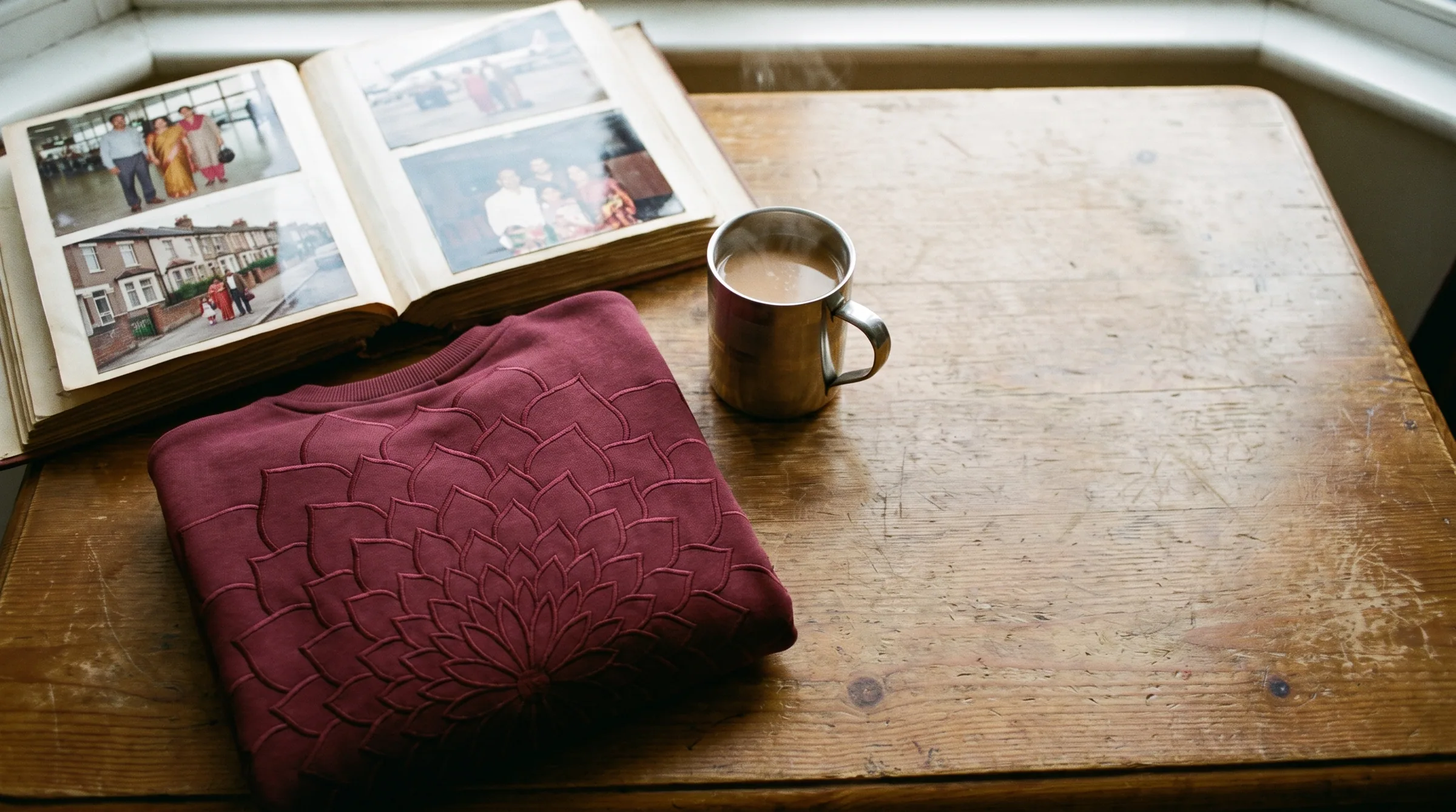 A family photo album open on a table beside a folded Pardes sweatshirt