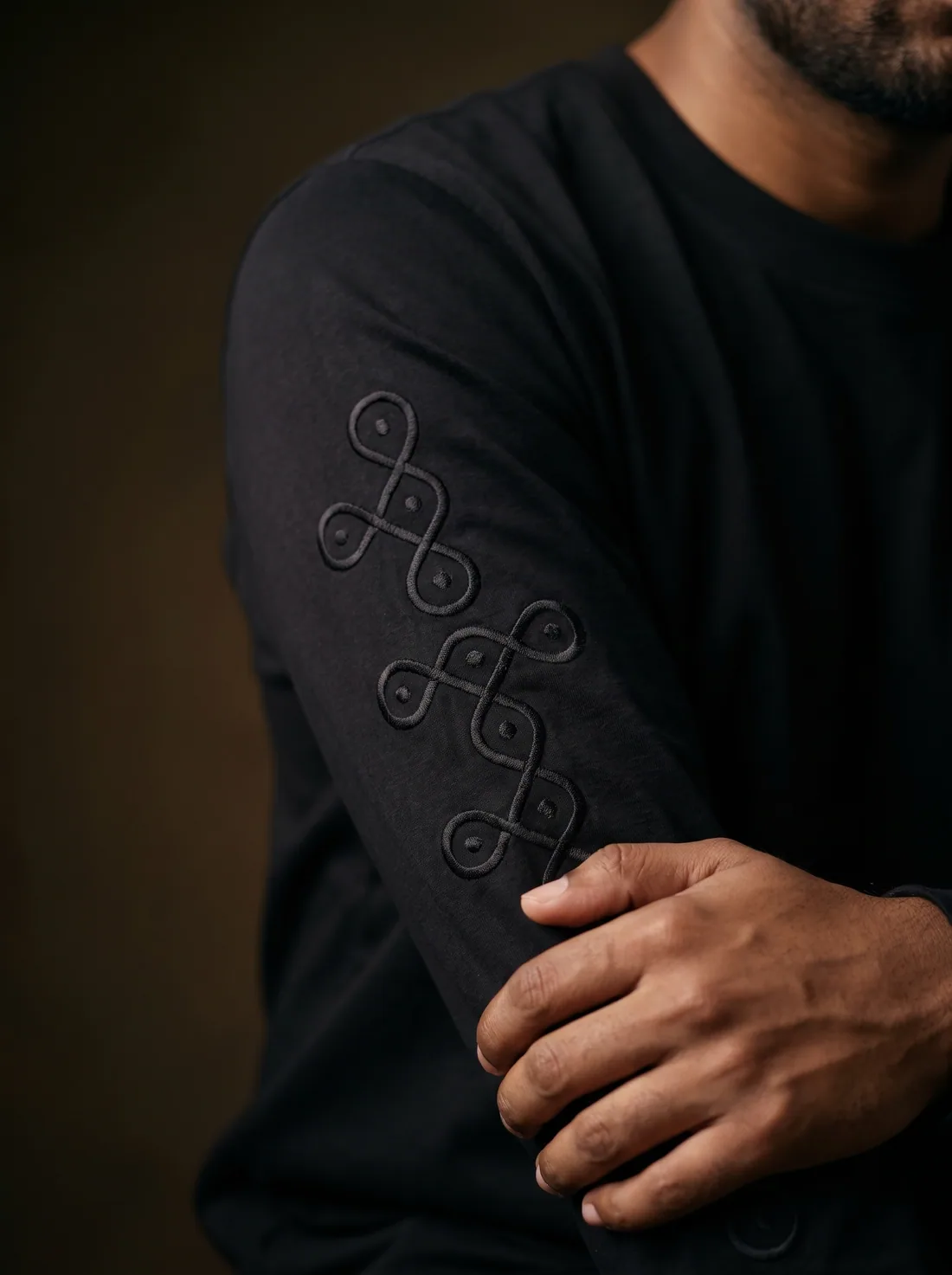 Tonal kolam embroidery running down a black sleeve