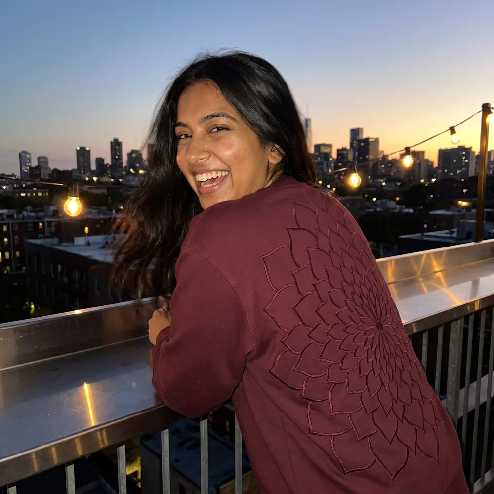 A customer in the Rangoli Sweatshirt on a rooftop at dusk